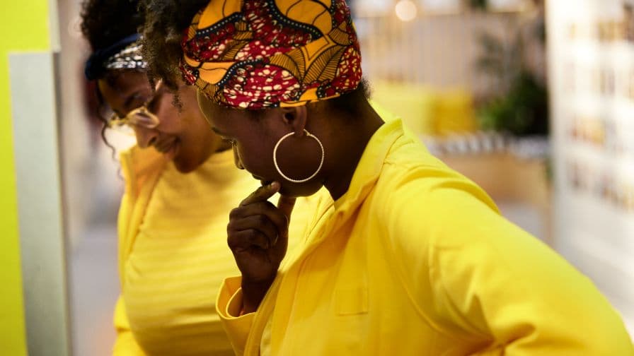 Two IKEA co-workers wearing yellow shirts and jackets looking down at something out of the frame.