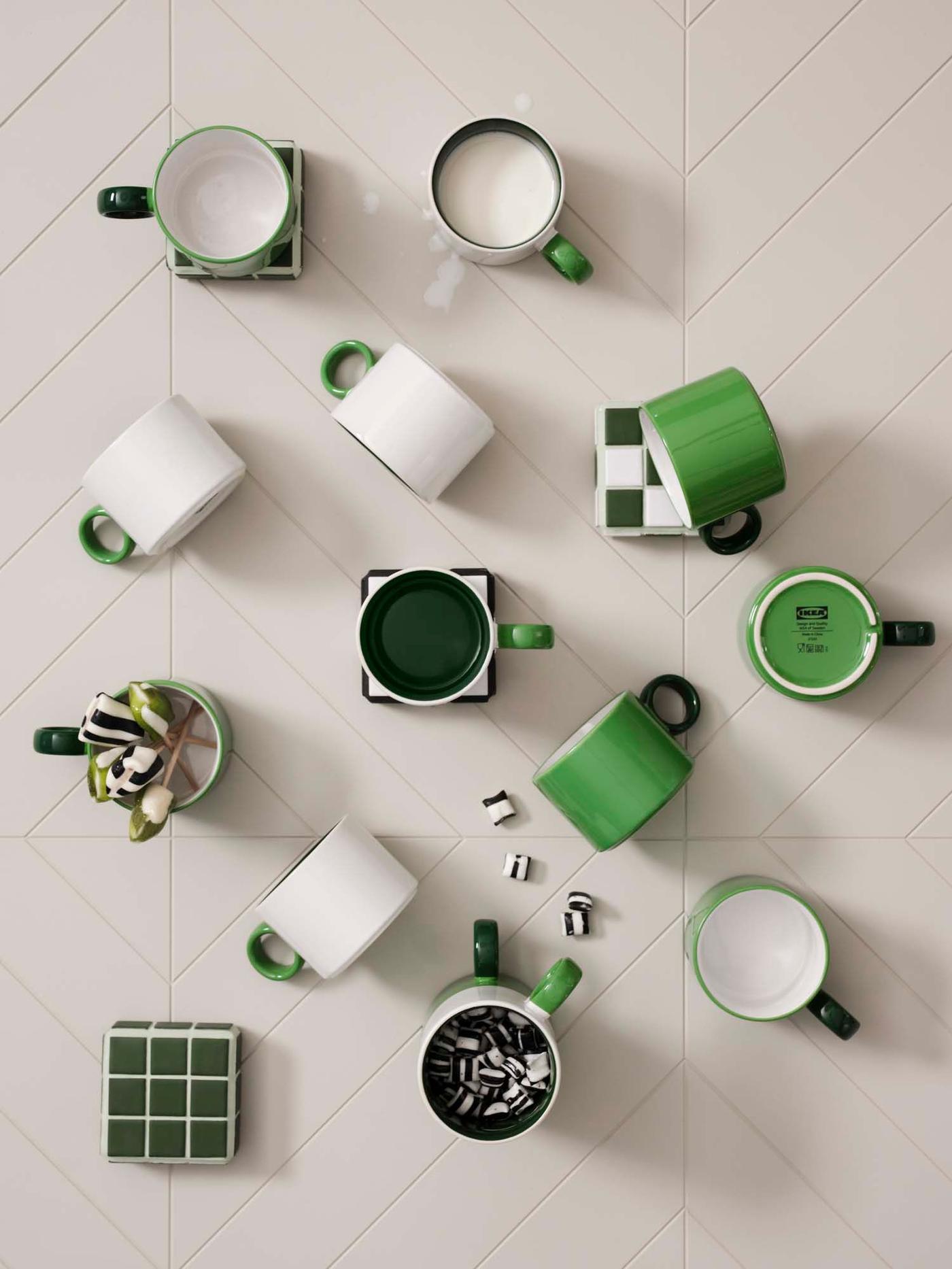 12 green and white cups are strewn across an off-white backdrop.