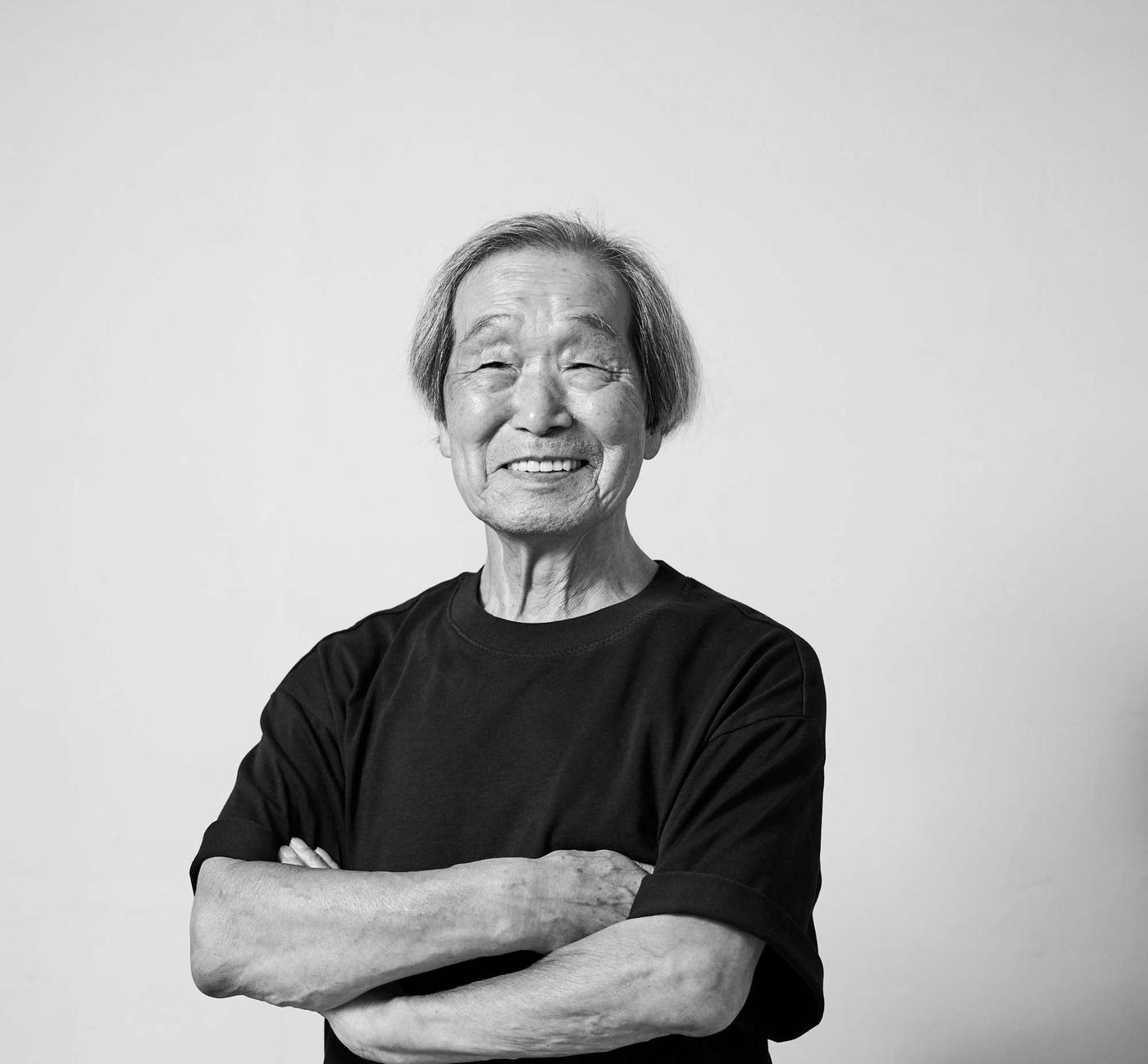 A black and white photo of designer Noboru Nakamura. He is smiling at the camera.