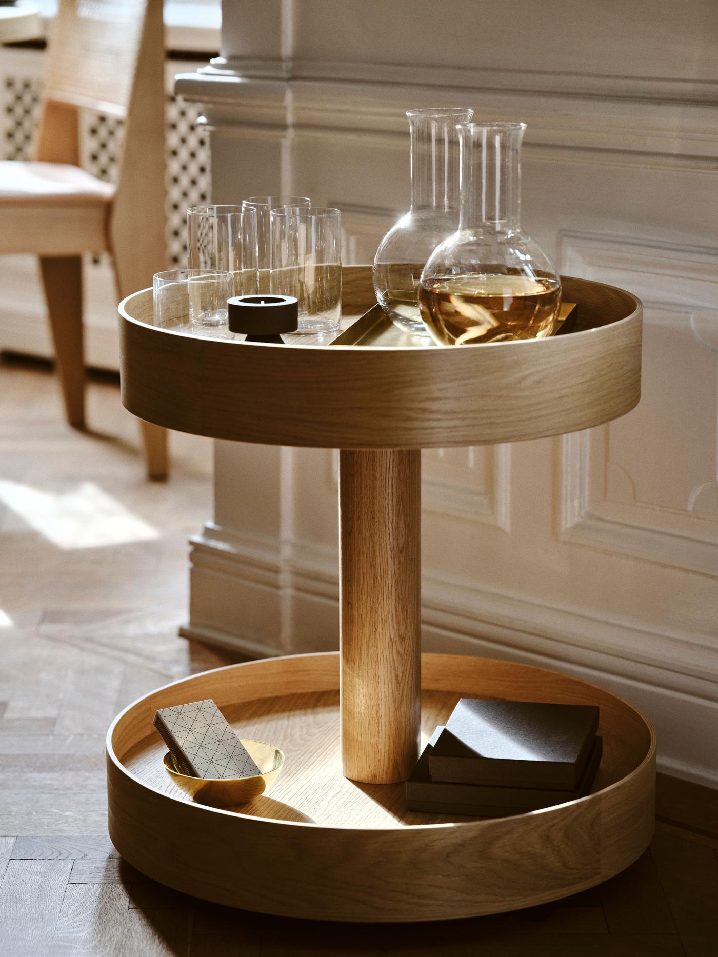 Round table in sunlight with carafes and glasses on top, blurred chair in the background.