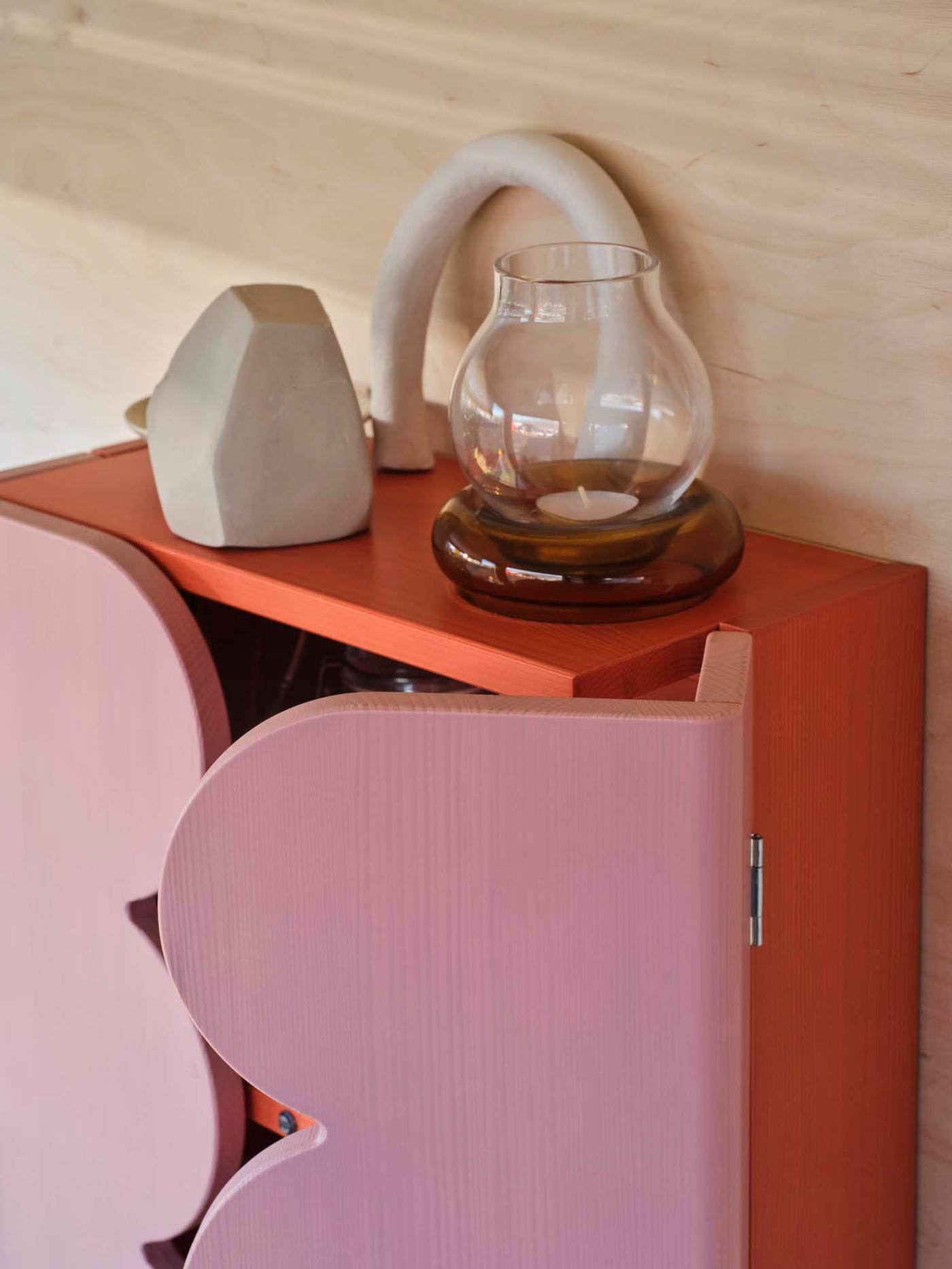 Objects are placed on top of a red and pink OMMJÄNGE wall-hung cabinet.