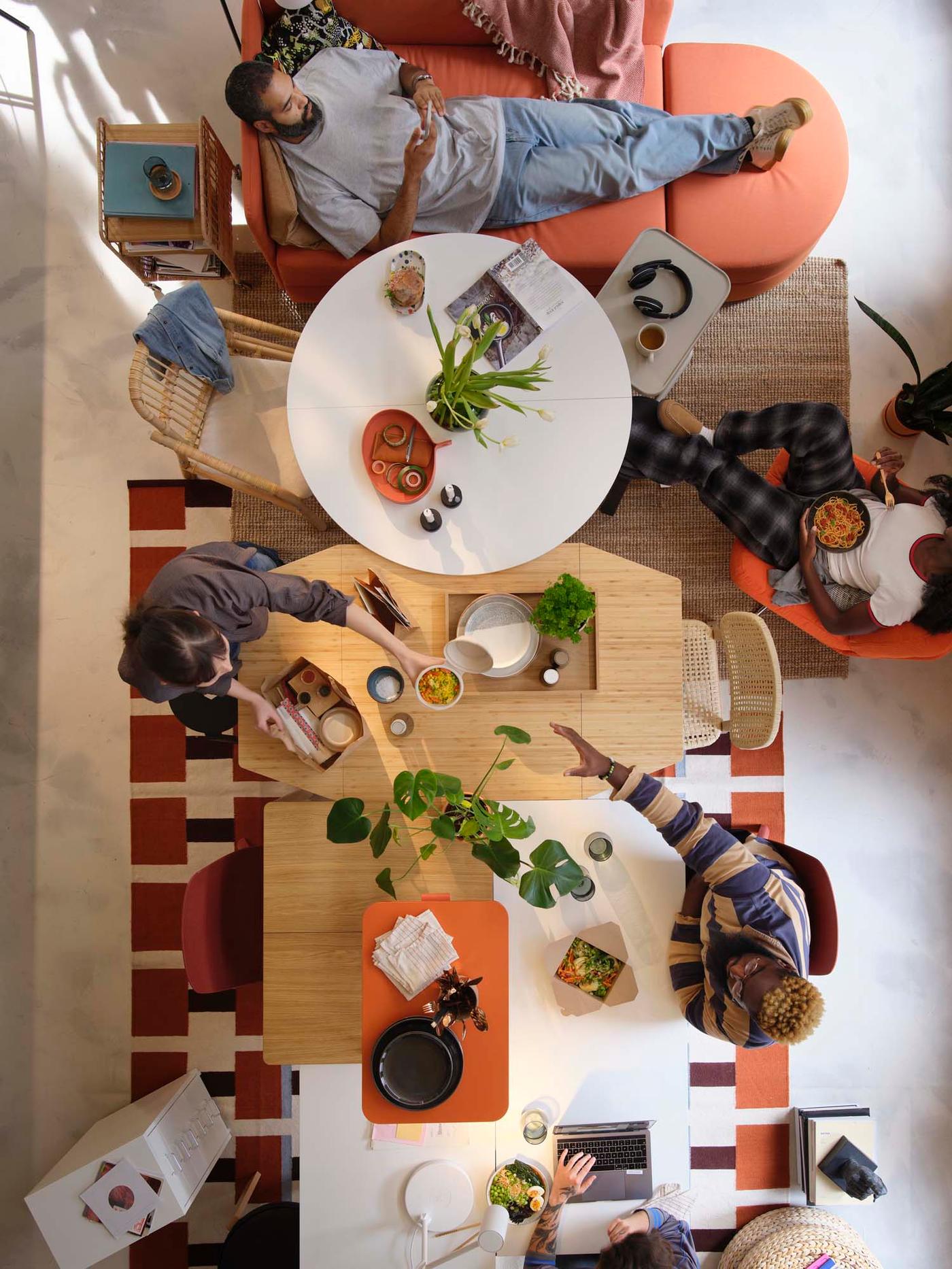 An overhead shot of people sitting around several different tables pushed together with mismatched chairs.