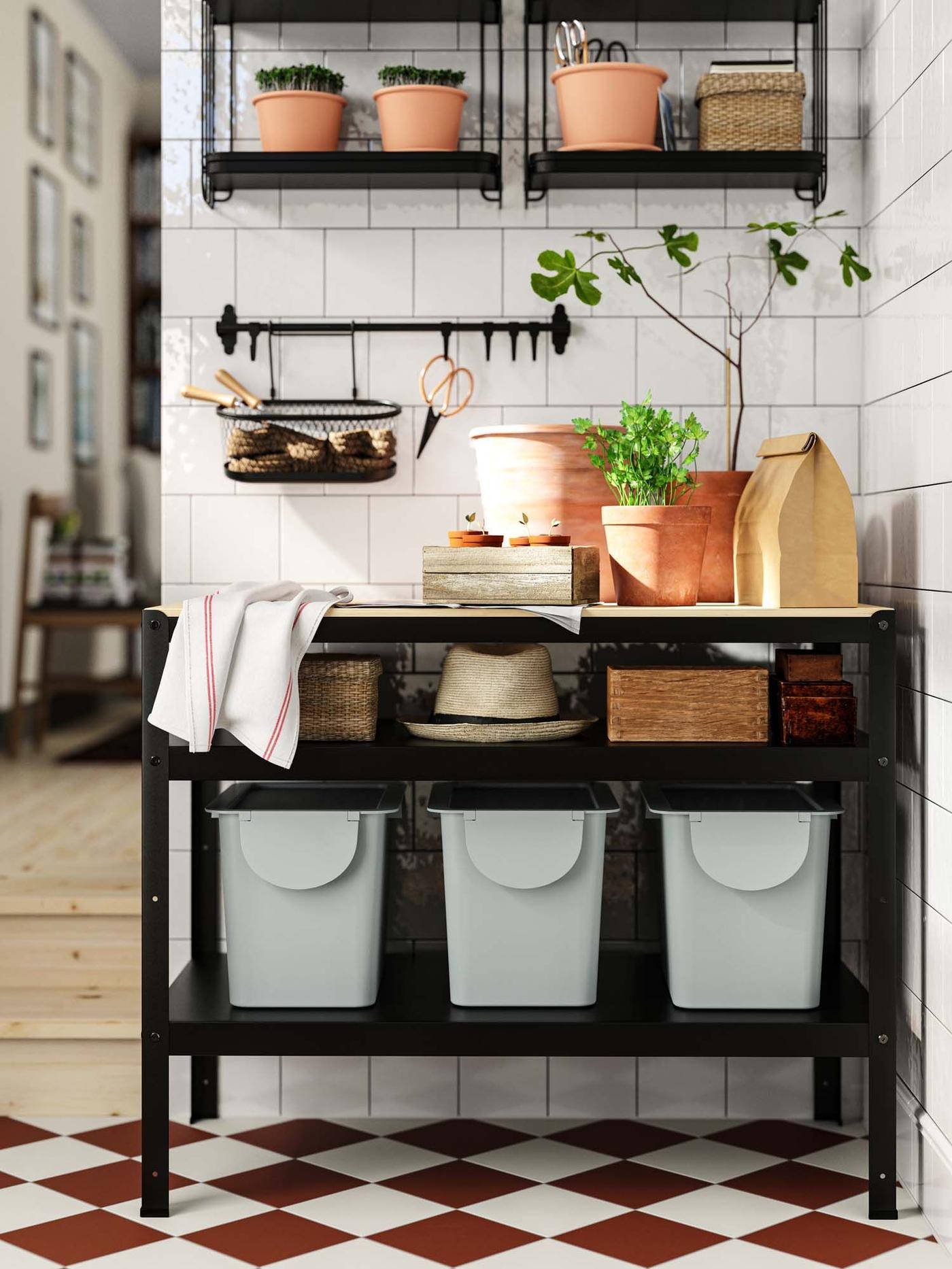 Three grey storage containers stand in a row on a black shelf.