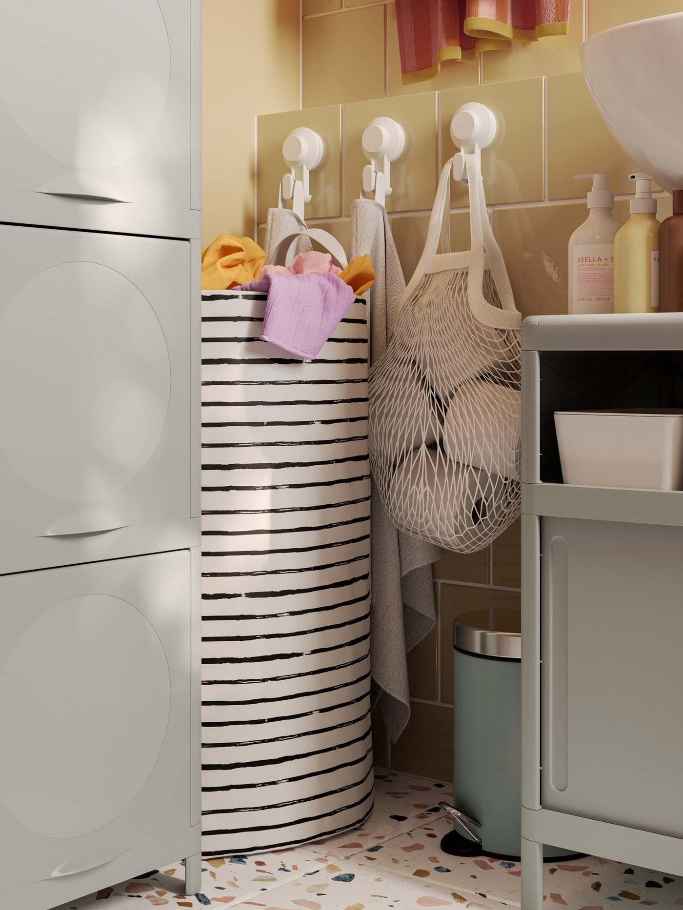 A small grey EKOLN waste bin in the corner of a bathroom.