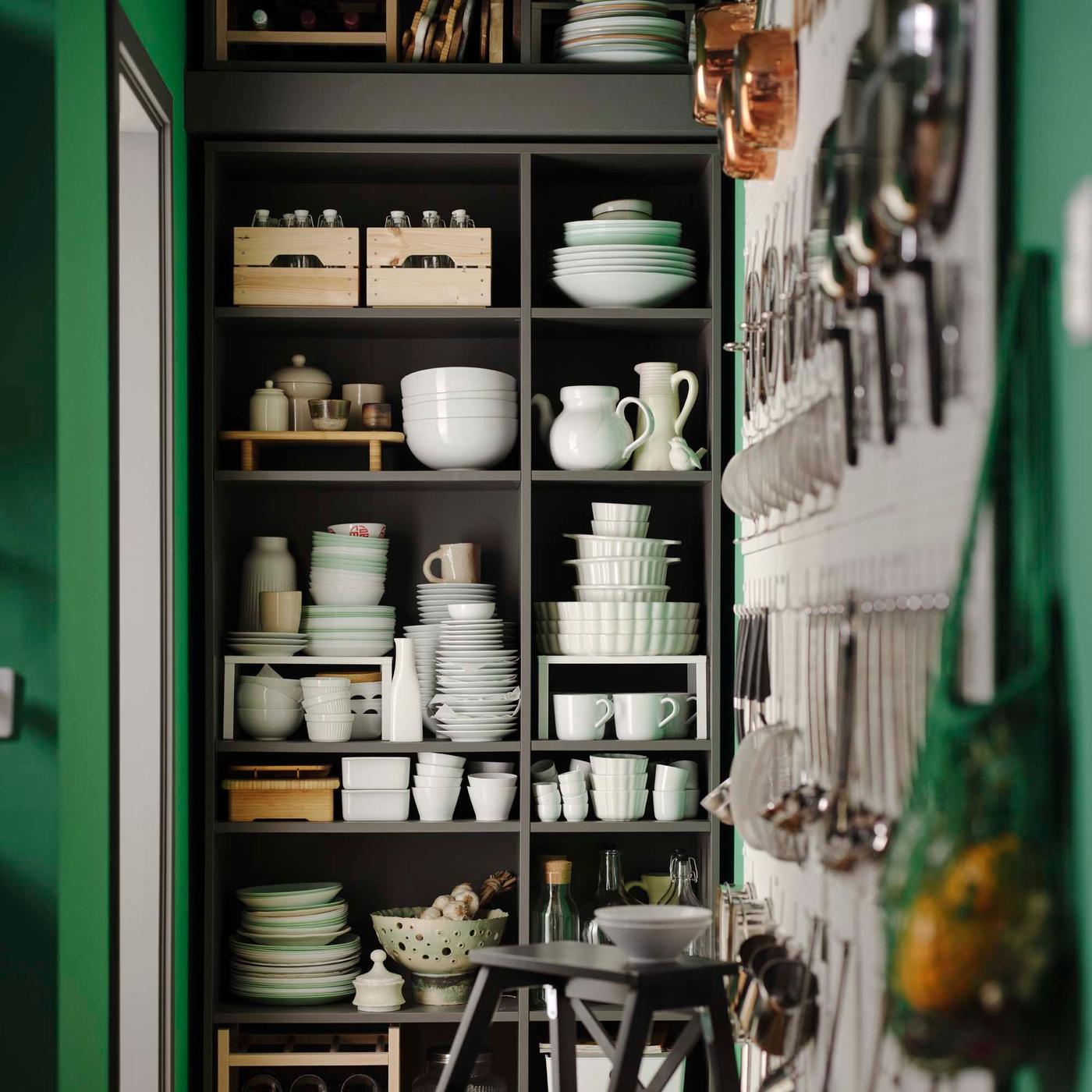 Wall-to-ceiling dark grey VIHALS shelving units filled with dinnerware and cookware.