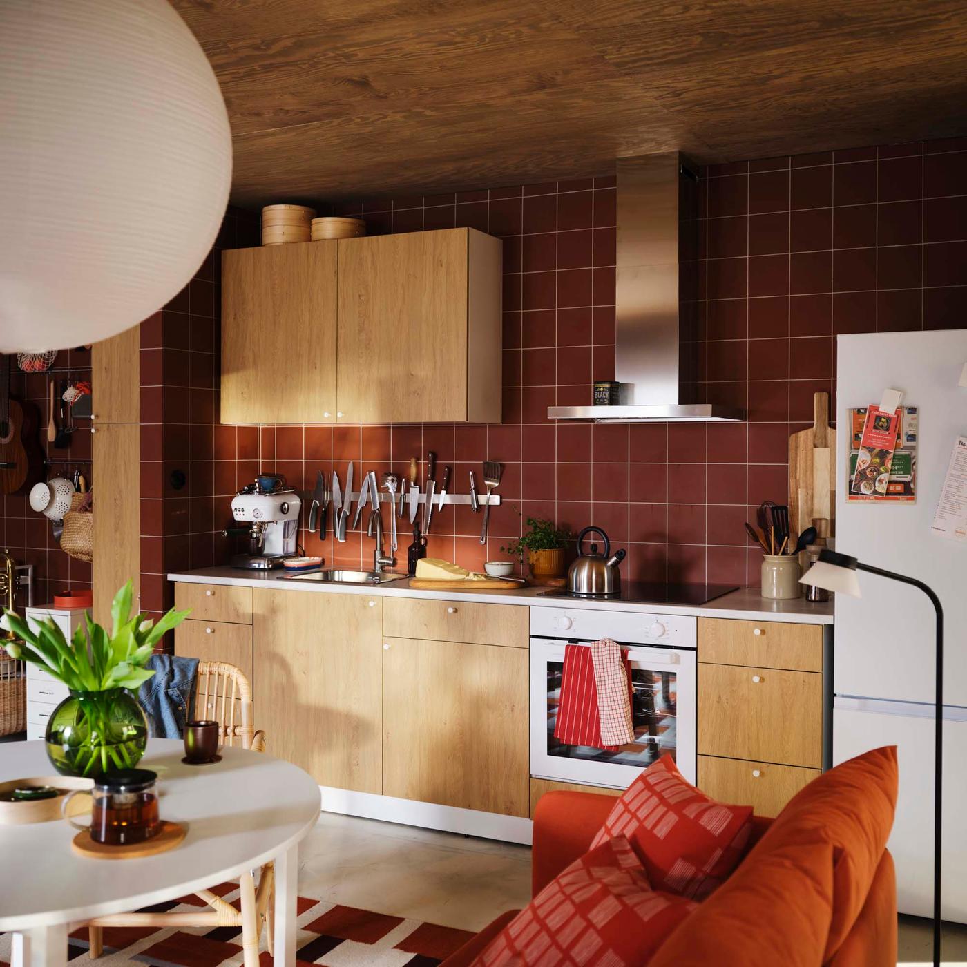 A white and oak-effect KNOXHULT kitchen with burnt orange tiles.