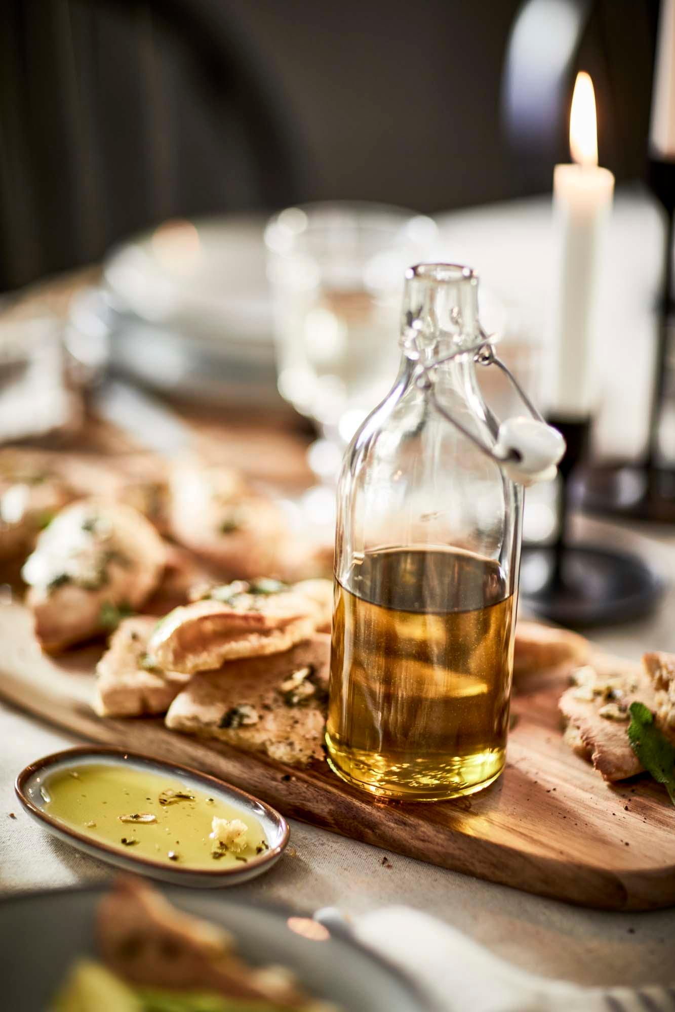 Fresh bread with a bottle of olive oil placed together on a wooden chopping board, ready to be served.