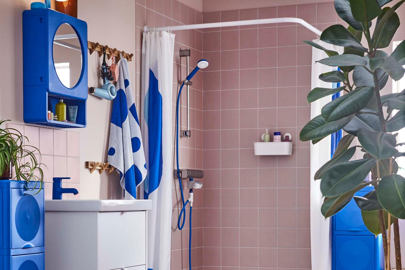 A pink, tiled bathroom with a big ficus plant and products from the BERGVATTNET collection.