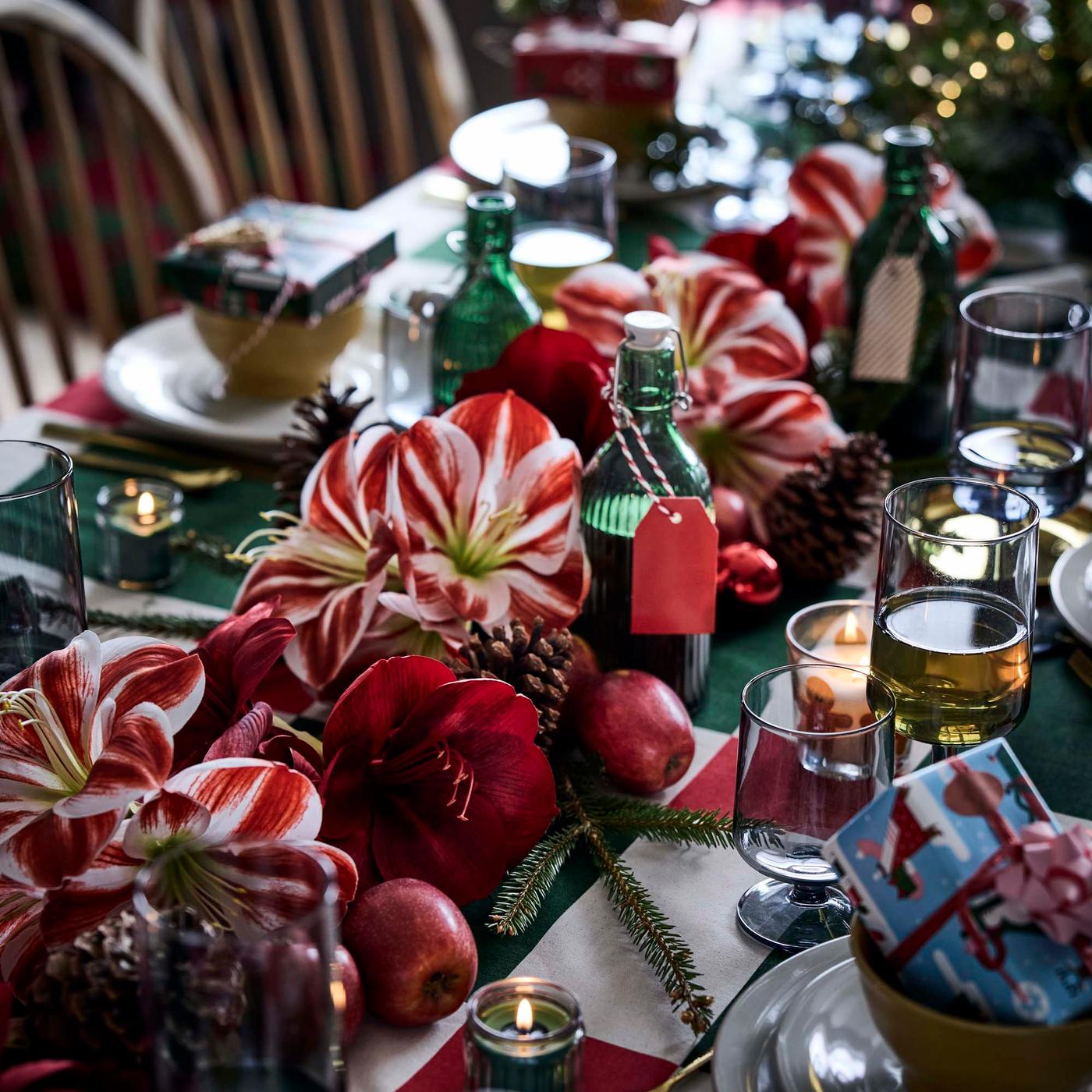 A red and white faux amaryllis garland running along the centre of a festive dining table.