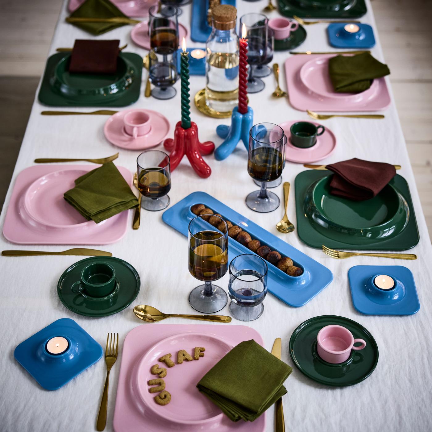 A selection of collection products in green, pink, and baby blue, arranged on a table set with napkins and glasses for several people.