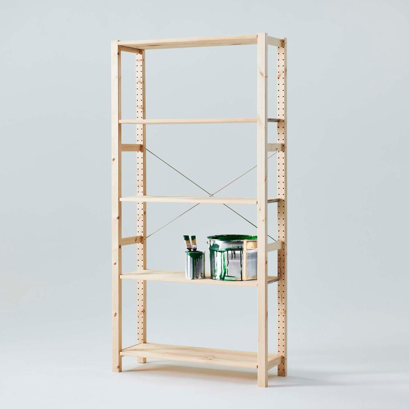 Two paint tins with paint brushes on the second to bottom shelf of an IVAR shelving unit in a light grey environment.