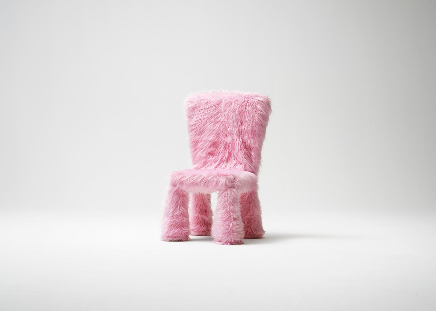 A children's chair with pink textured furry cover placed on a white background.