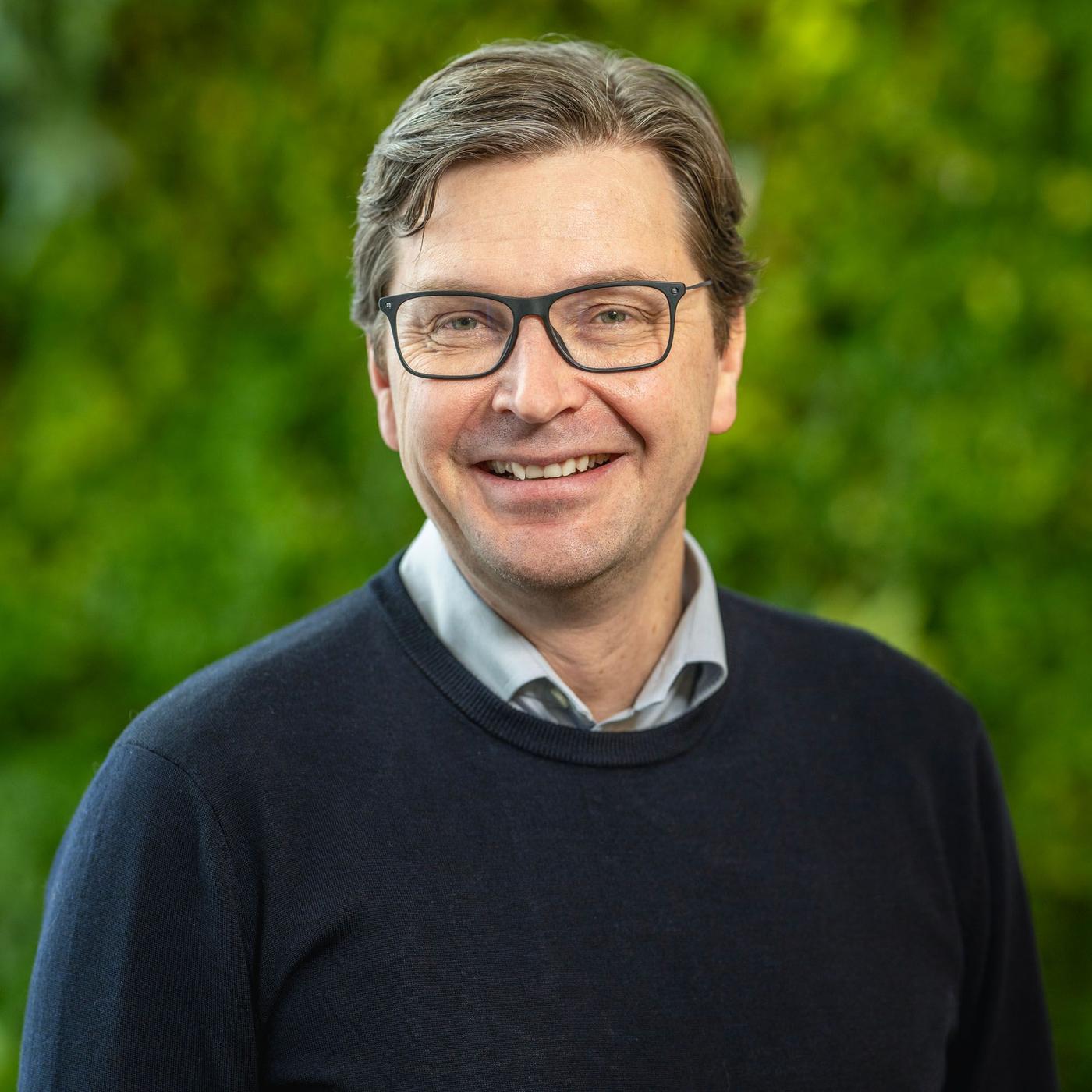 Pär Stenmark standing with a green plant wall in the background behind him.