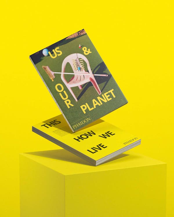 Two copies of the book Us & our planet float above a yellow plinth.