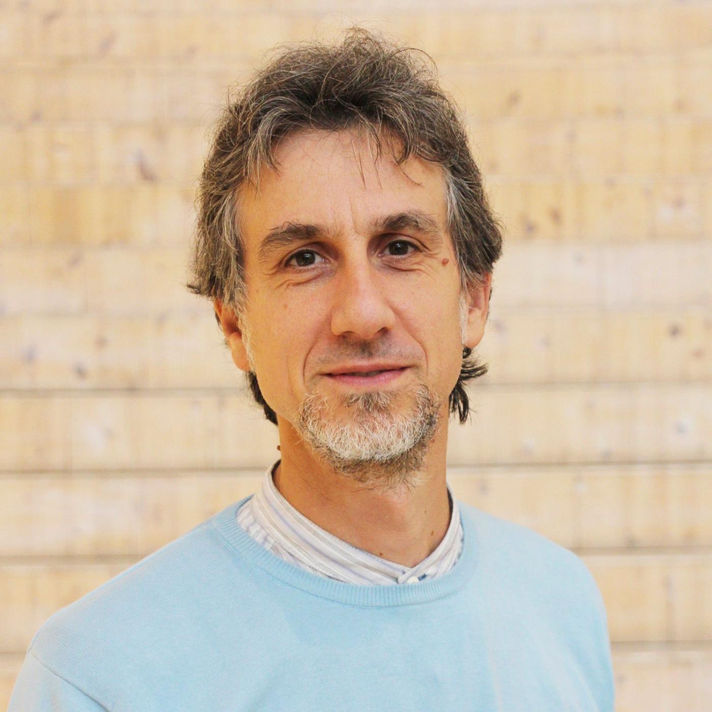 A portrait of a man with a beard in a light blue shirt.