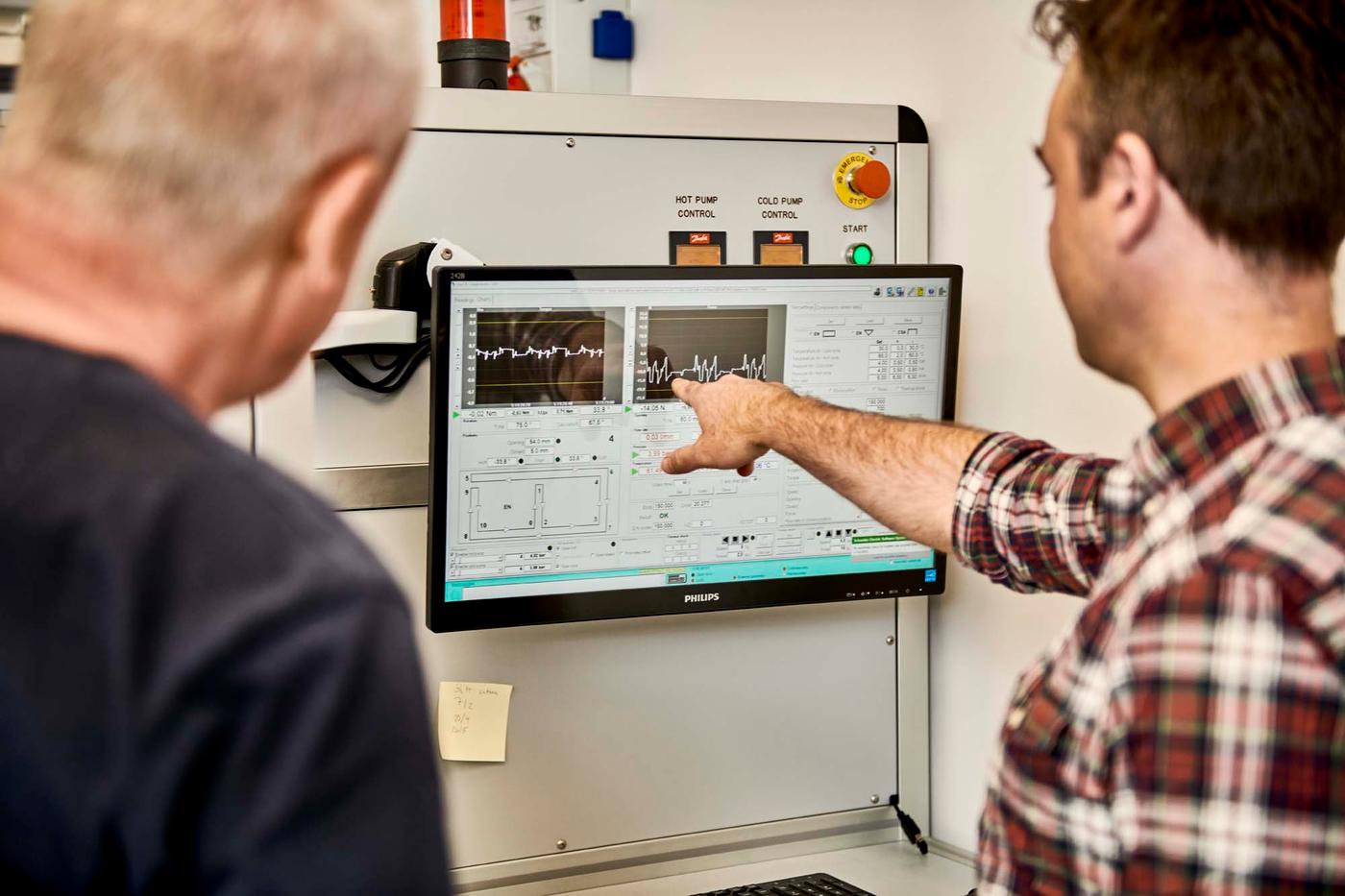 René points at a screen depicting data while in the test lab with a colleague.