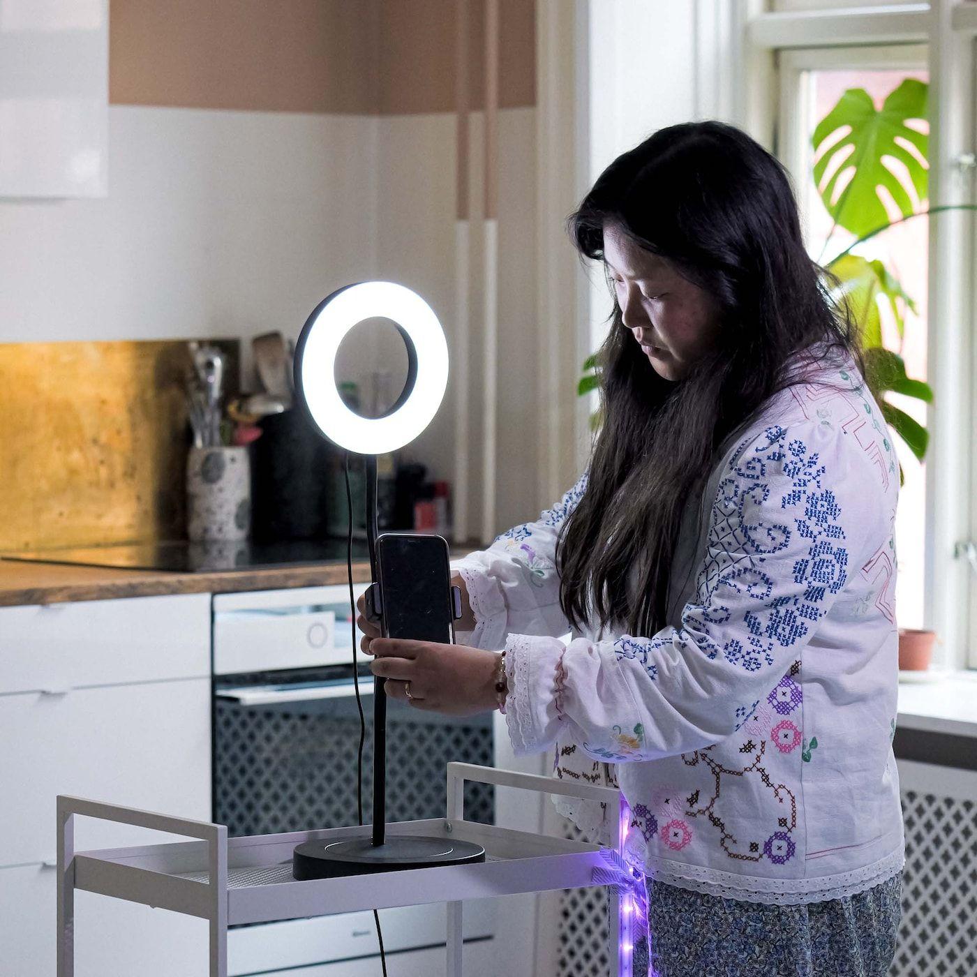 Rosa inserts her smartphone into the LÅNESPELARE lamp