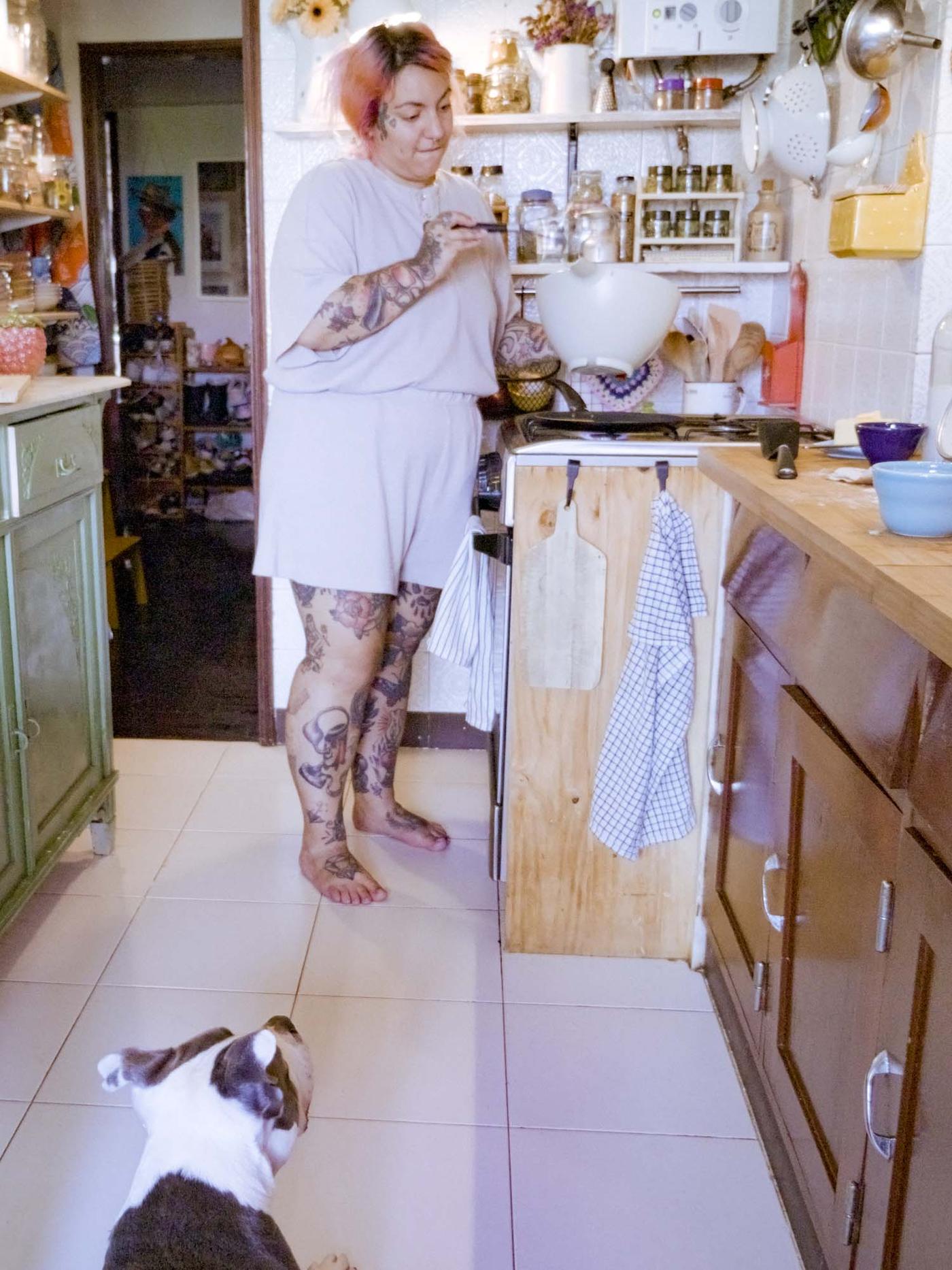 Denise makes pancakes in the kitchen, while the dog watches.