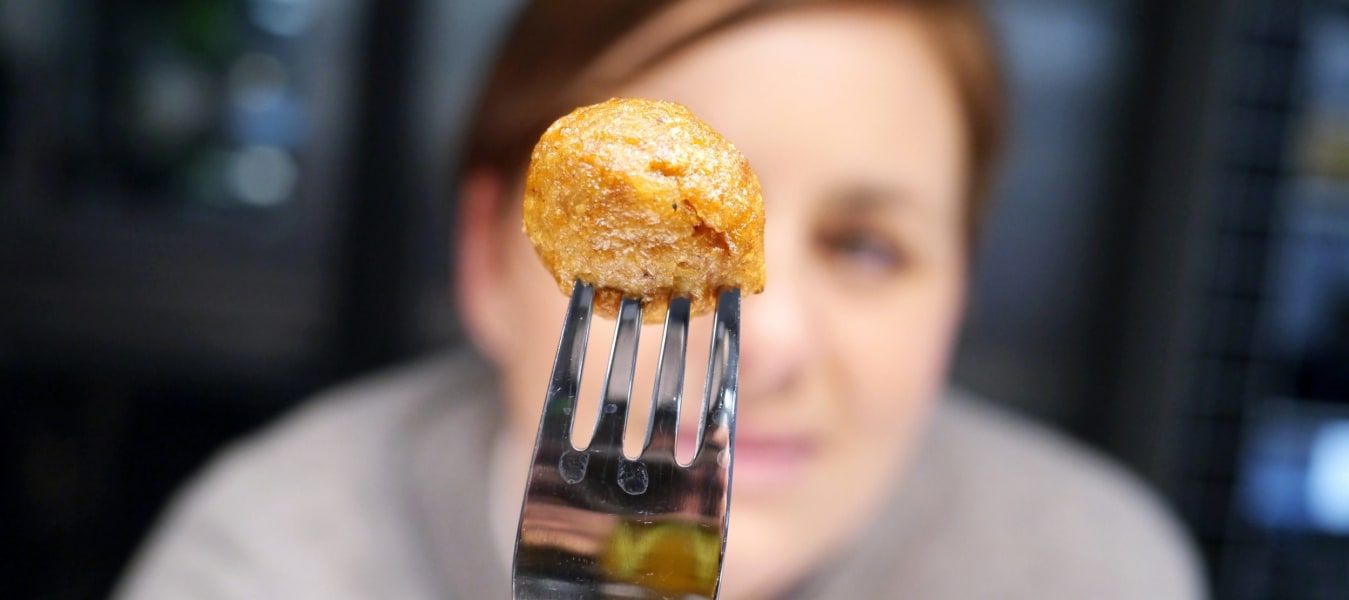 A woman holding a fork with a plant ball on it.