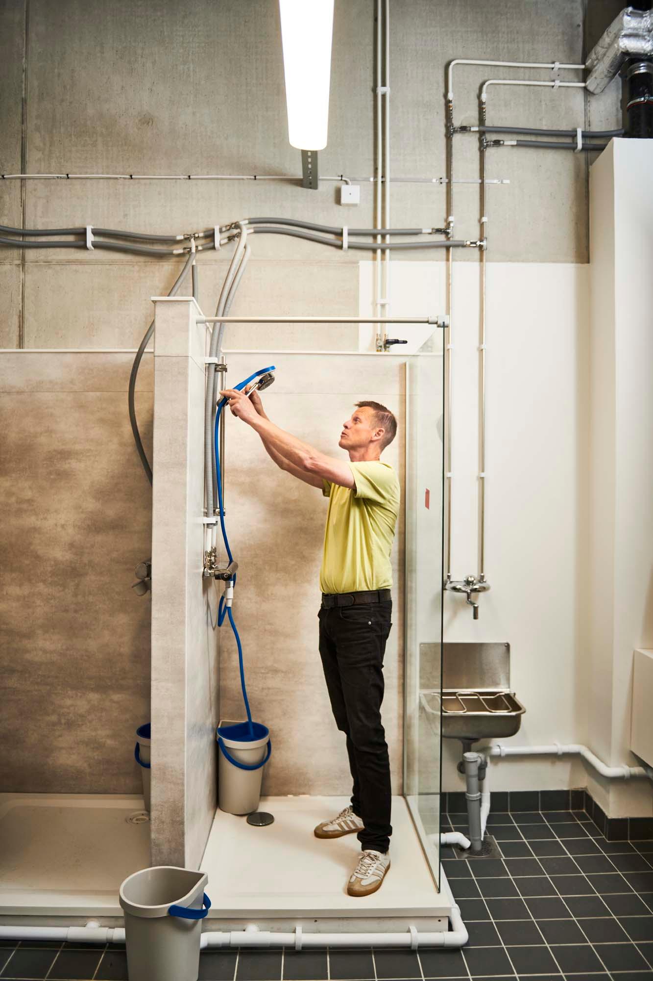 Tobias adjusts a BERGVATTNET single spray hand shower with hose in the test lab.
