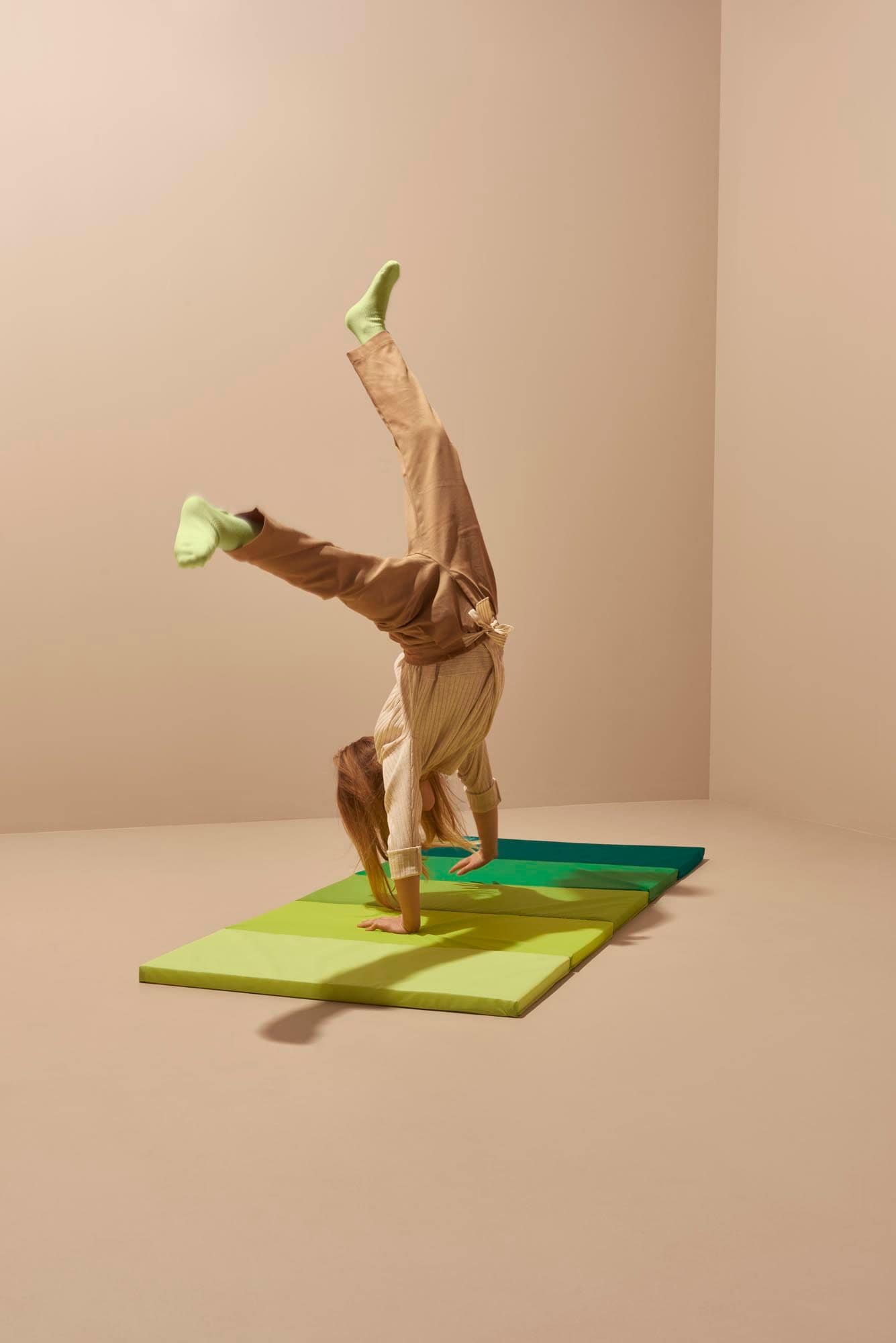 A child does a handstand on a PLUFSIG folding gym mat.