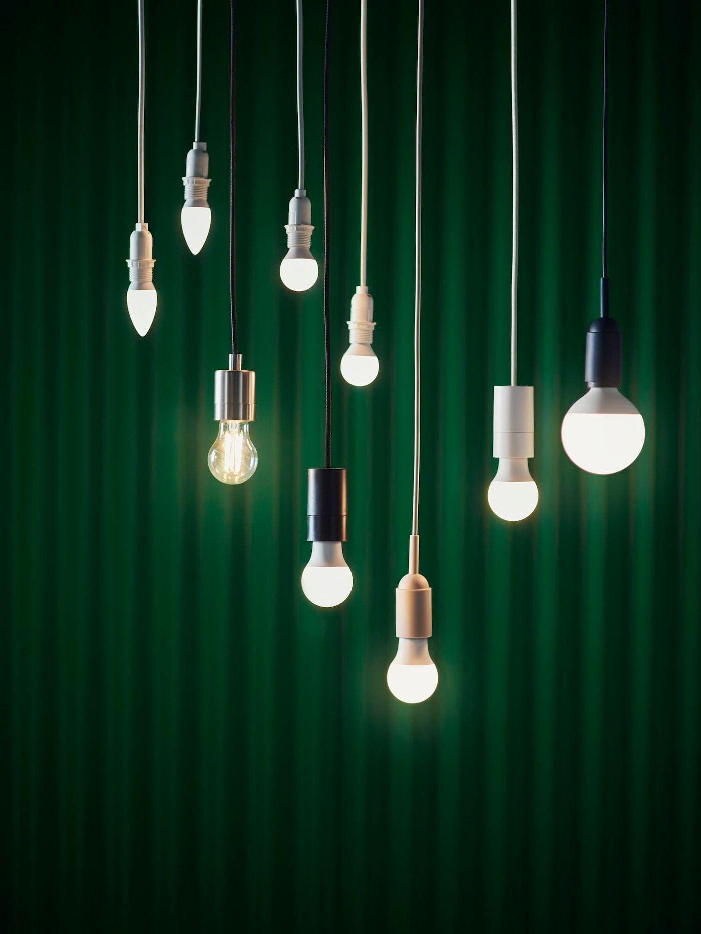 Various SOLHETTA bulbs hang from cables against a green curtain backdrop.