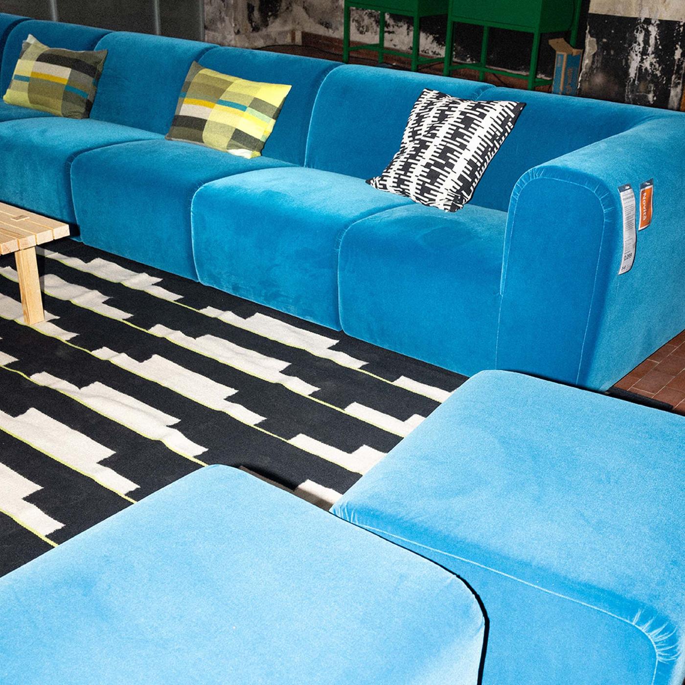 A blue STOCKHOLM sofa and a light wood table on a black and white patterned rug.
