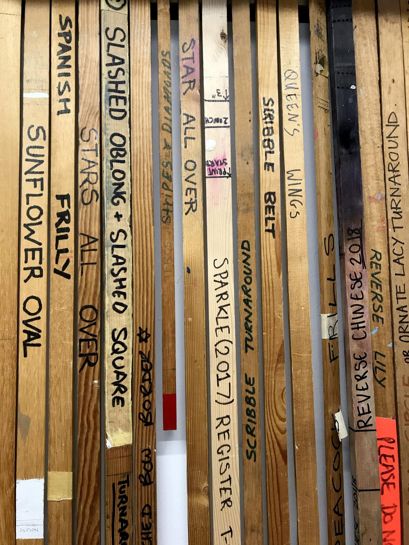 A number of wooden pieces hanging in a row with handwritten information on them.