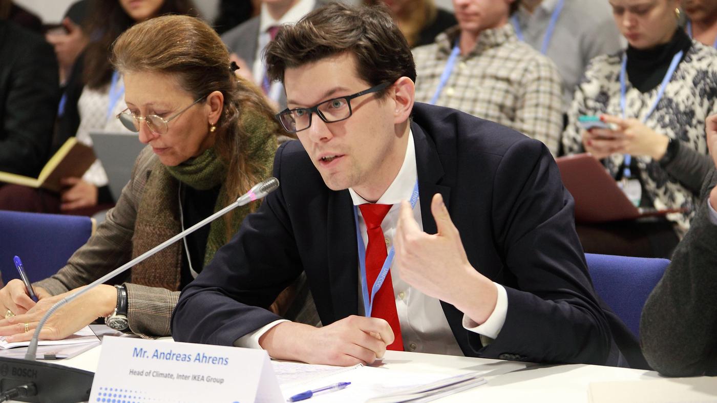 A man with a tie, speaking at a conference.