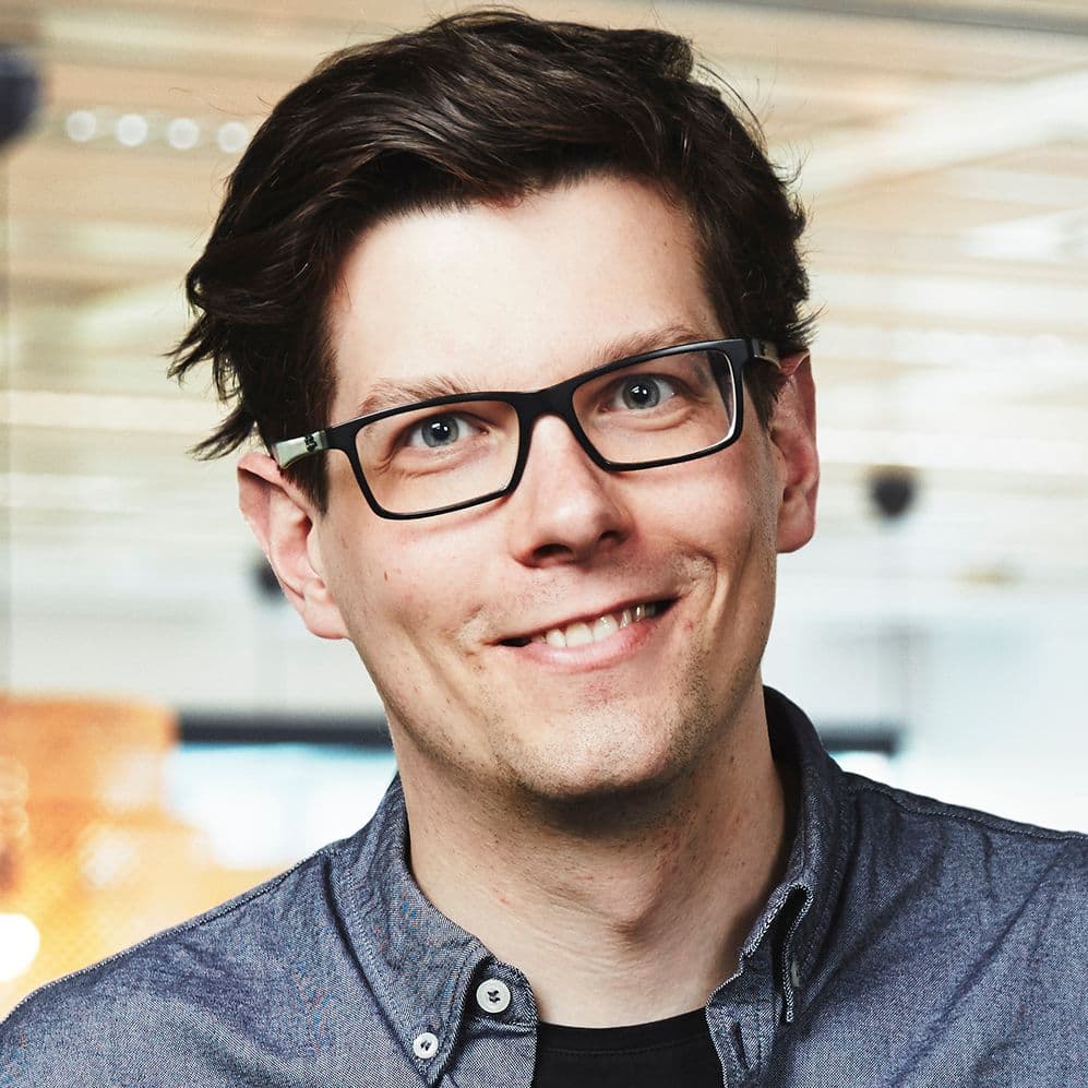 A portrait of a man with brown hair and glasses.