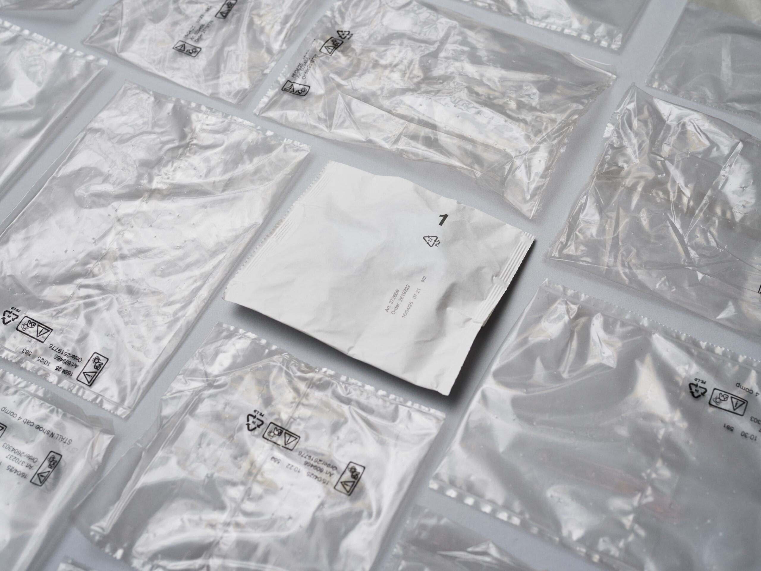 A flat paper-based fitting bag next to similar plastic fitting bags.