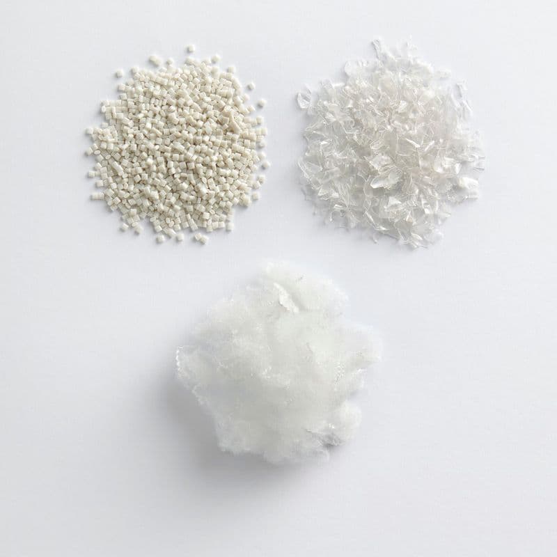 White plastic materials in three piles on a white surface; one fluffy, one in flake form and one in pellet form.