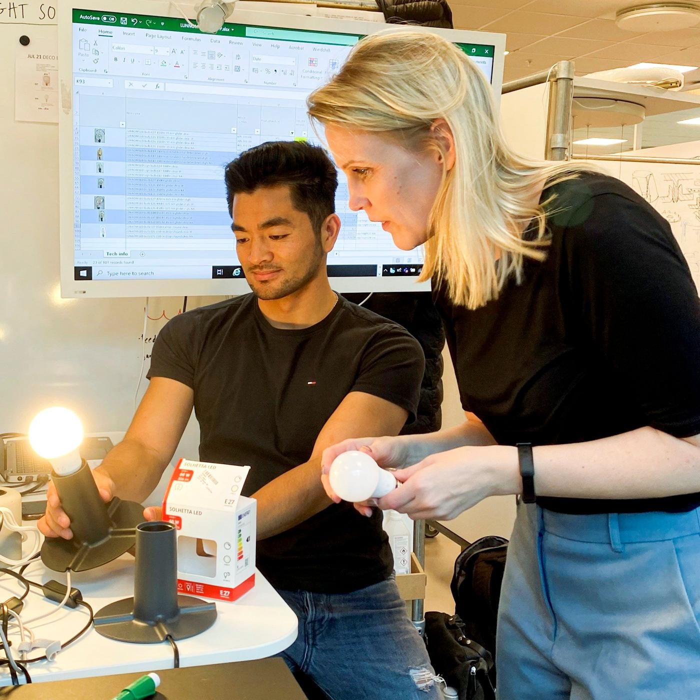 A man and a woman in a test environment, holding LED bulbs.