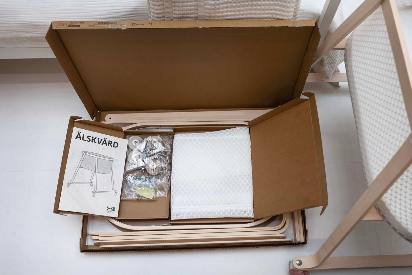 An open cardboard flatpack package showing the bassinet, with assembly instructions.