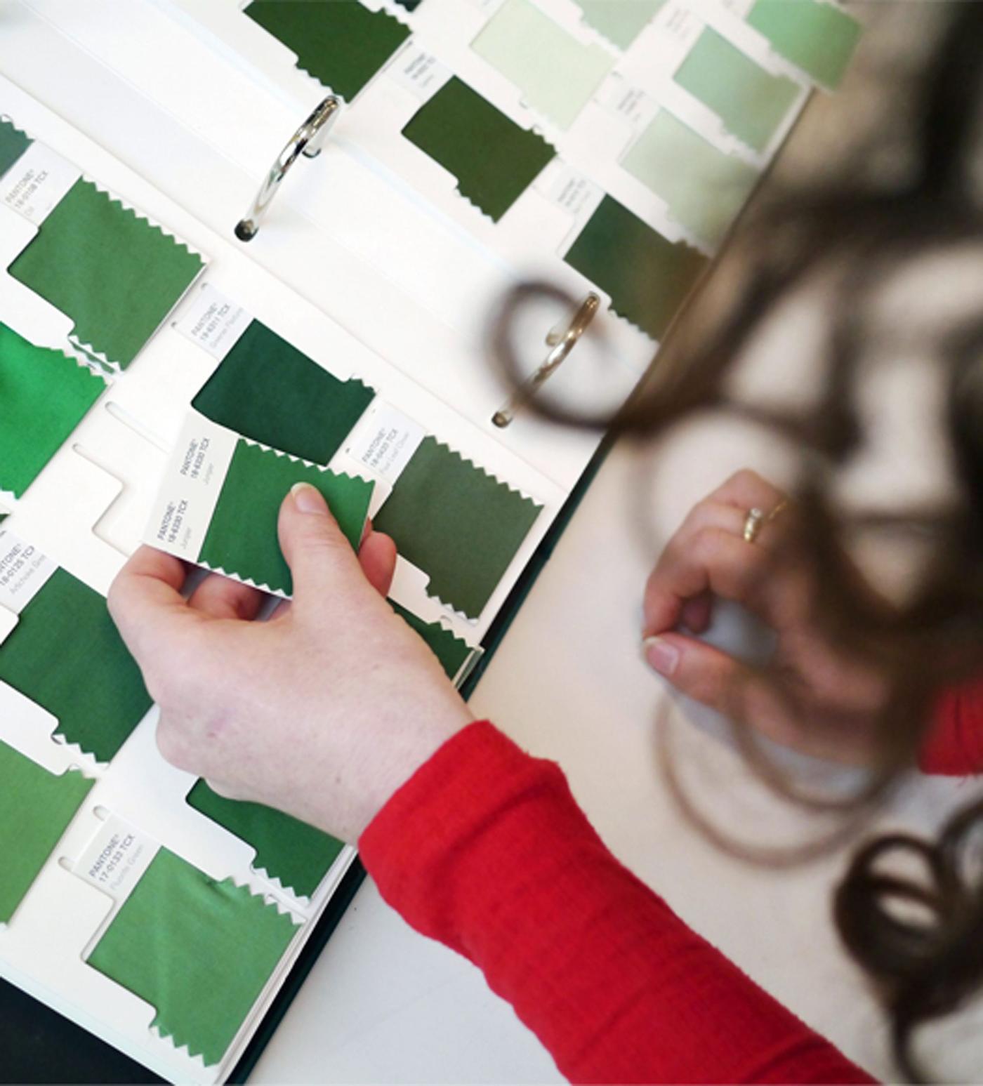 A woman going through a chart with textile samples in green.