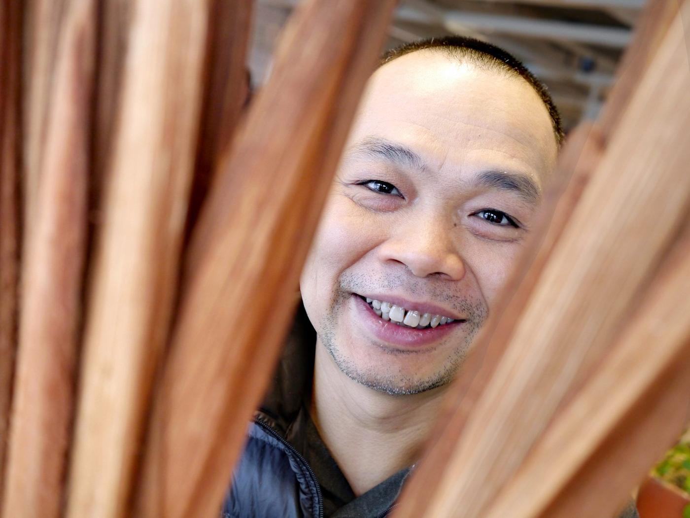 Portrait of a smiling man surrounded by brownish nipa palm leaves.