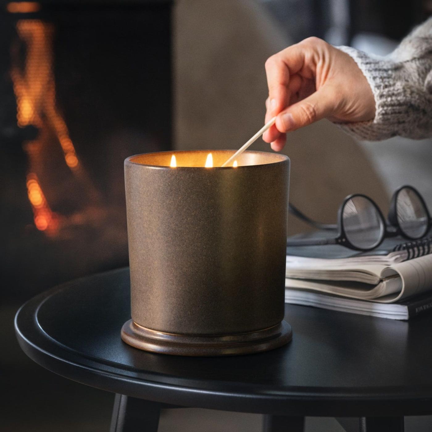 A hand holding a match lighting a candle.