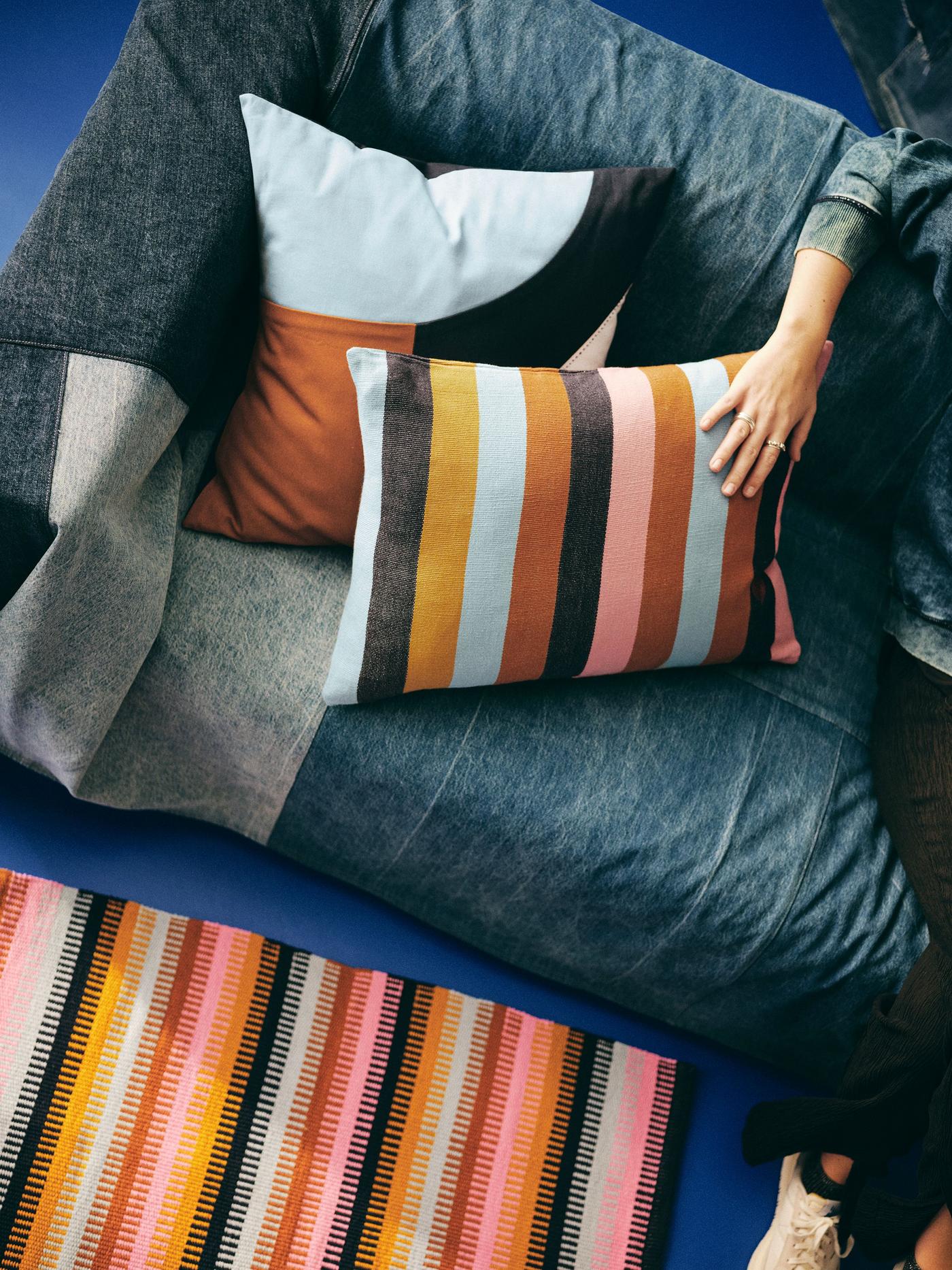 Two pillows in a sofa, one person sitting next to the pillows and holding a hand on one of them.