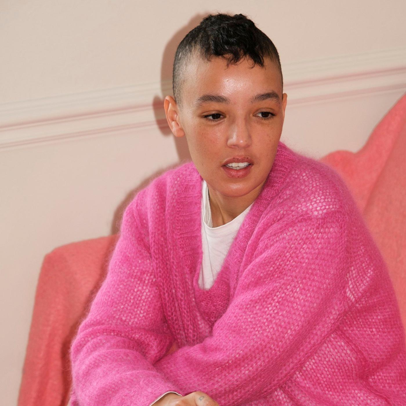 A girl in a pink sweater sitting in a sofa