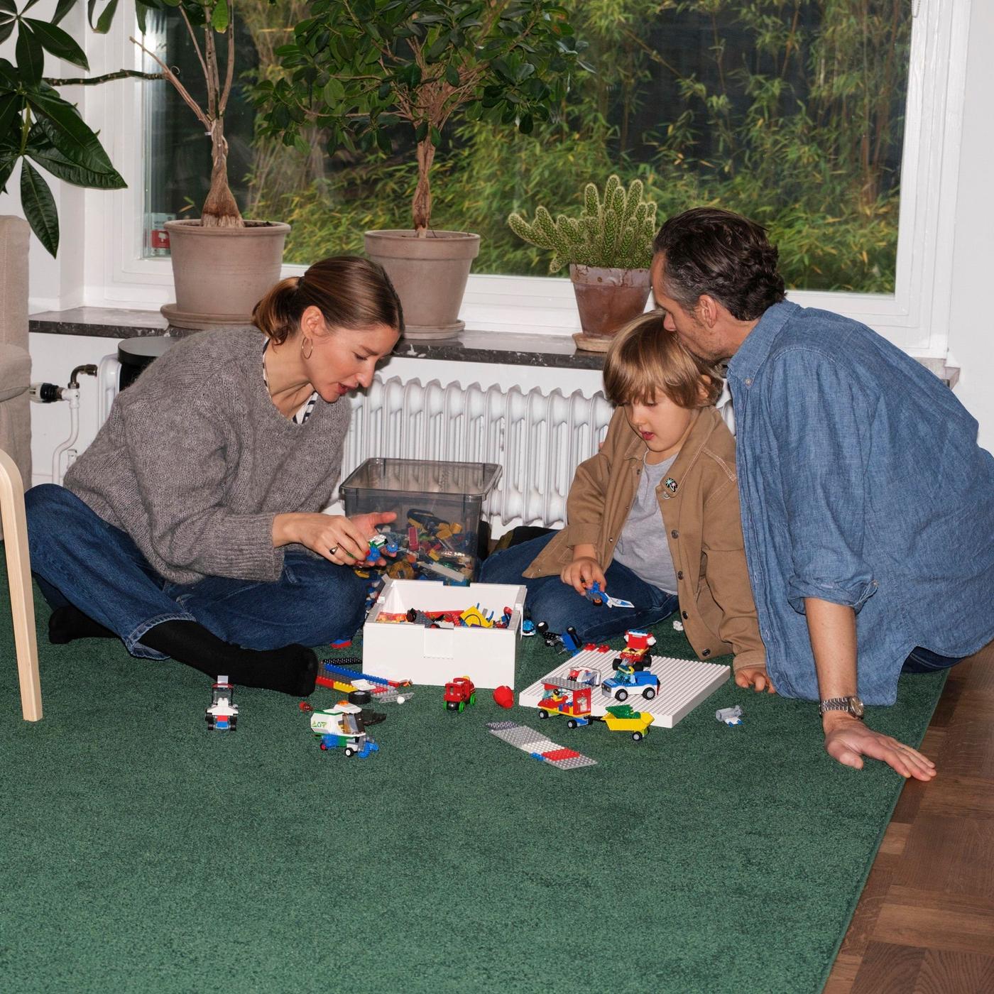A woman and her man sitting on the floor playing with their son.