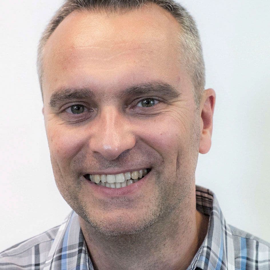 Portrait of a man in blue-grey plaid shirt.