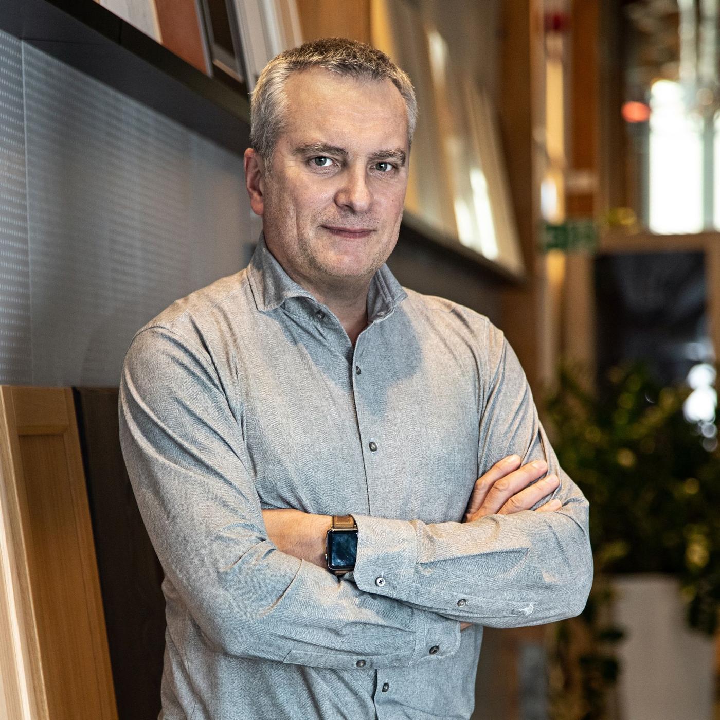 Portrait of a man in a grey shirt standing with his arms crossed.