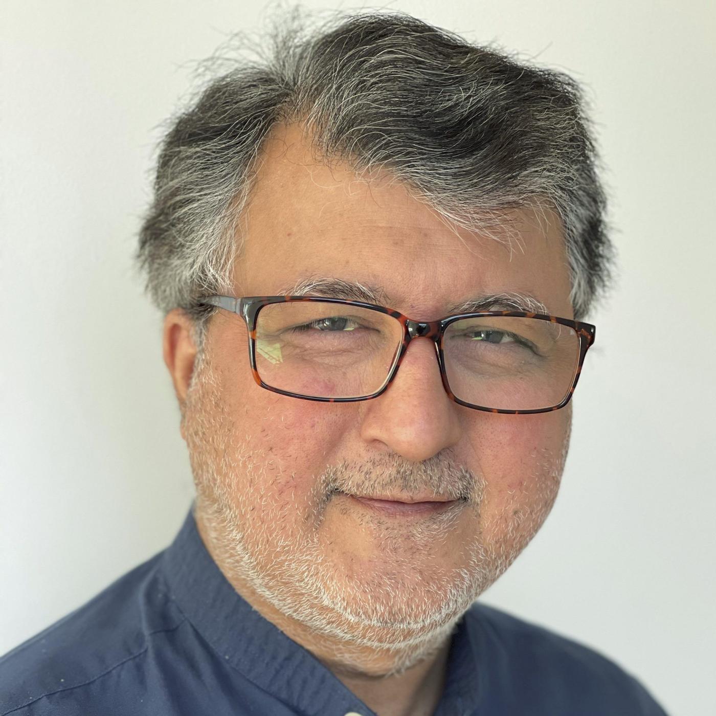 Portrait of a man in glasses with a blue shirt.