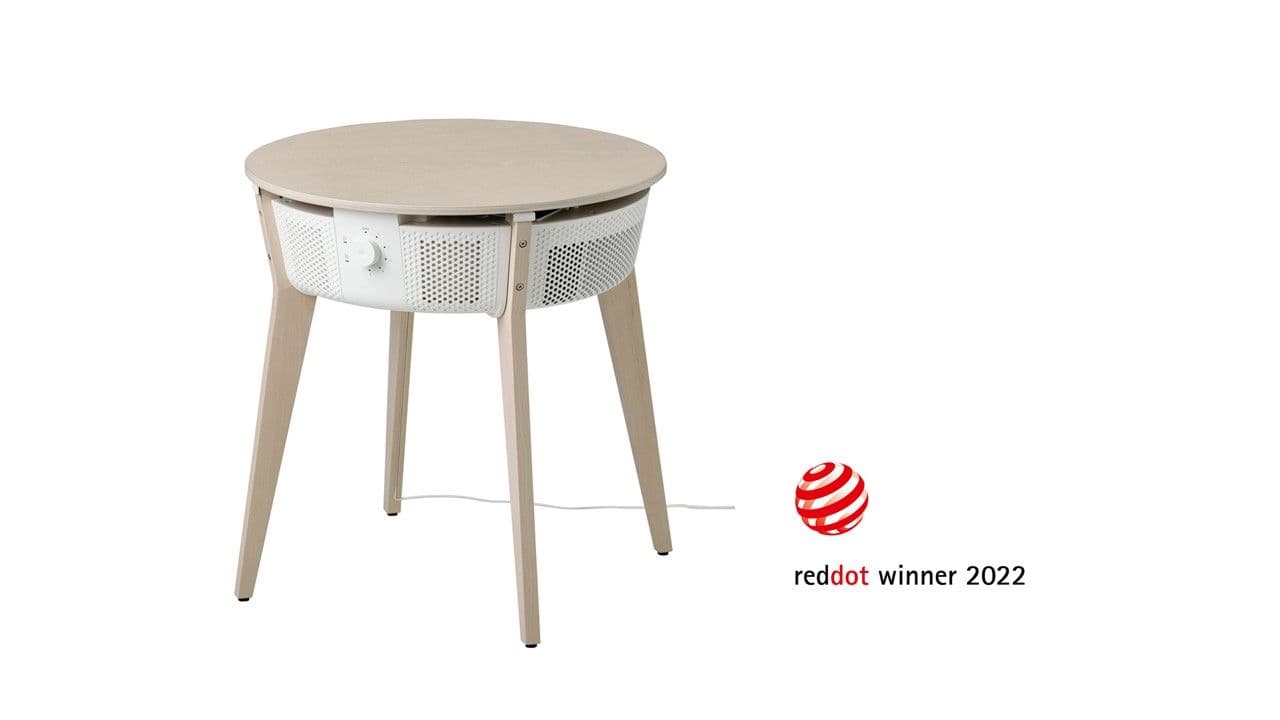 A table with an air purifier below the table top. There is a red and white logo in the corner.