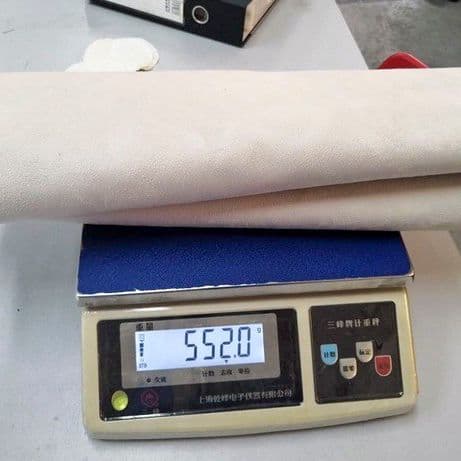 Two rolled up pieces of fabric on a blue and beige digital scale, on a white tabletop.