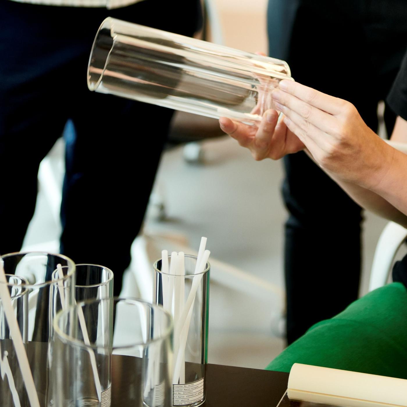 A pair of hands holding a glass vase.