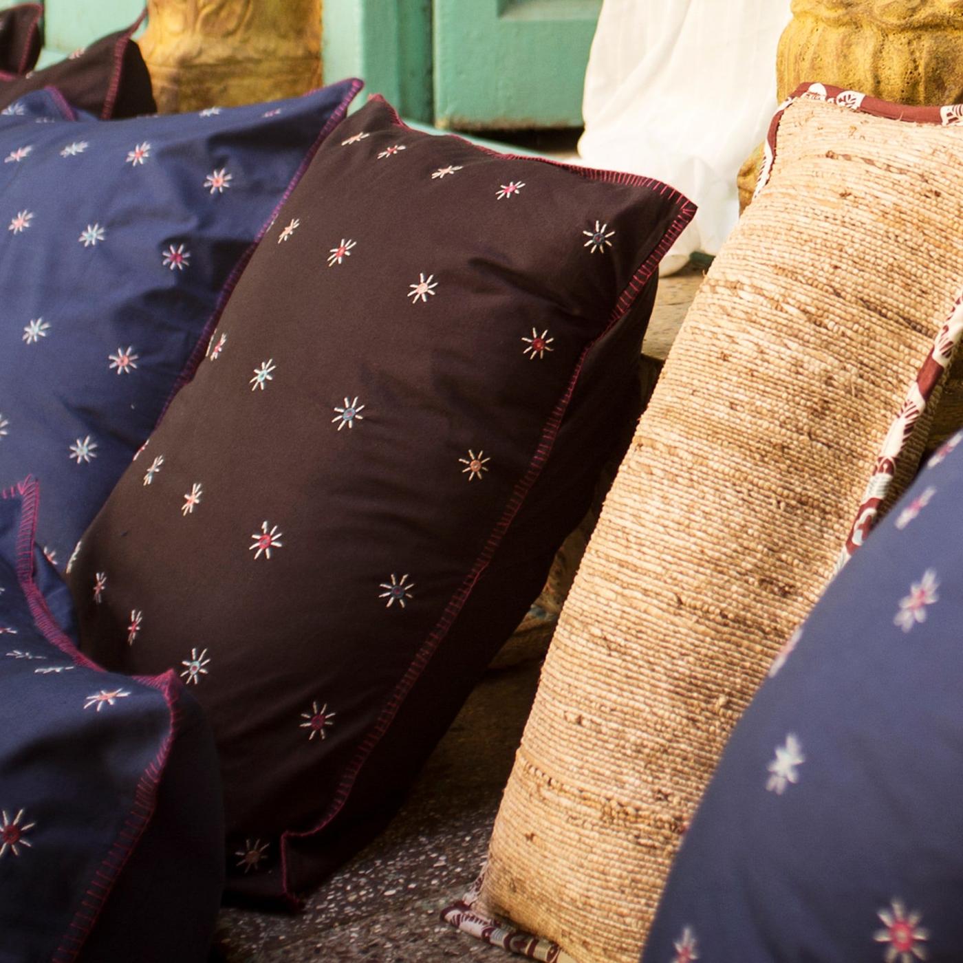 Hand-embroidered STADIGT cushions in different sizes, colours and materials, like fabric and hand-woven banana fibre.