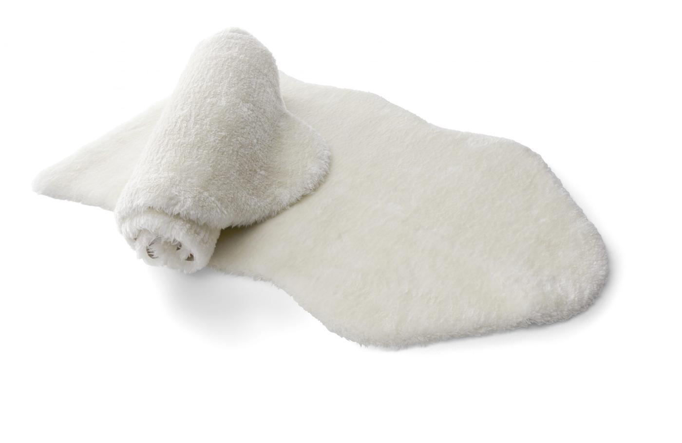 Two white fake sheepskins; one is rolled up and lies on top of the other.