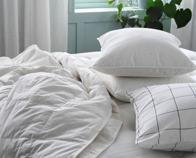 An unmade bed with white bed linen.