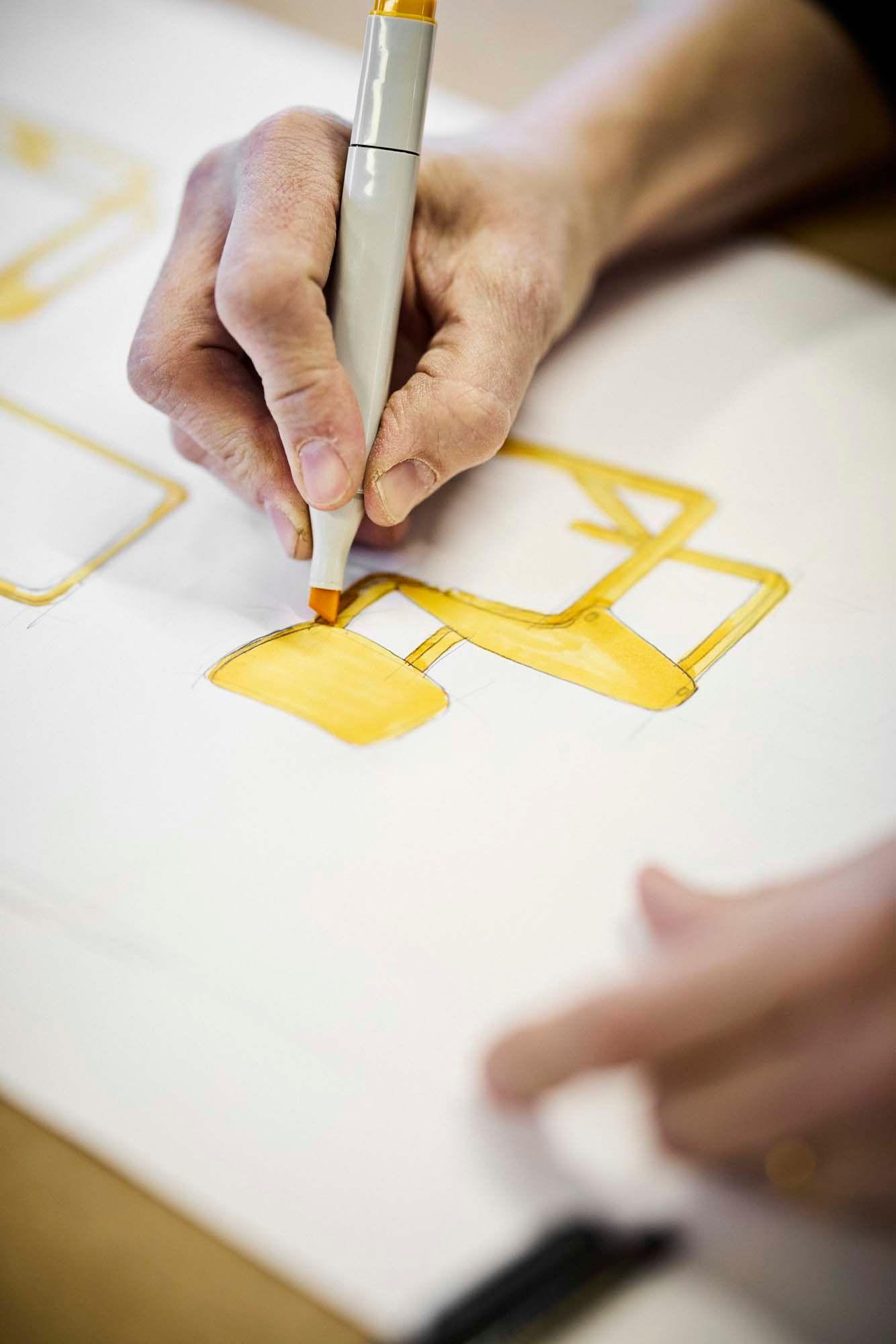 A hand drawing a sketch of a yellow LYCKAN chair.